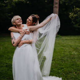 two brides with long white clothings laughing together